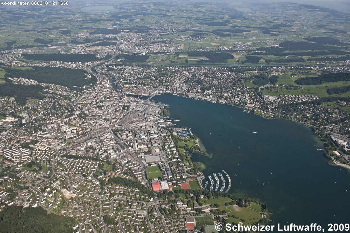 KKL, Universität, Bahnhof Luzern: Bildmitte. Bildrand unten Mitte: Tribsche; Bildrand links Mitte: Kriens; Bildrand rechts obere Mitte: Ebikon; obere rechte Bildecke: Zugersee; am oberen Rand links: Hallwilersee und Baldeggersee; oberer Bildrand links: Sempachersee mit Sempach; 'BaBel'-Quartier am linken Reuss-Ufer in der ersten Flussschlaufe.